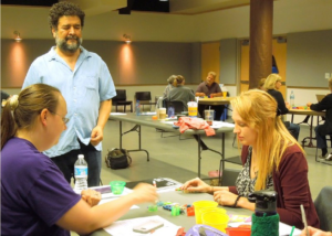 Jesús watching participants at a conference learning to play PORTL.
